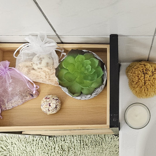 Badekugel auf einem Holzwagen neben der Badewanne, mit Pflanze , Kerze und Naturschwamm