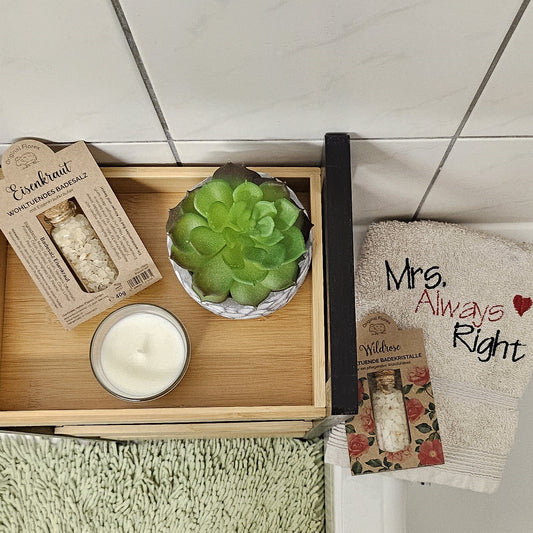 Eisenkraut Badesalz und Wildrose Badesalz neben Badewanne, mit Pflanze und Handtuch – Draufsicht