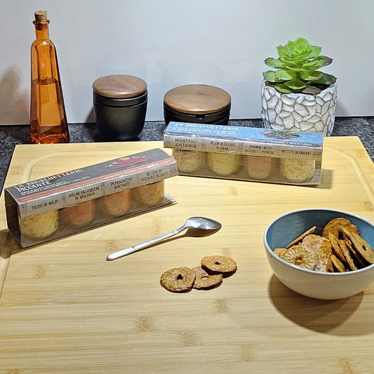 Bruschetta Creme Geschenksets auf einem Holzbrett neben einer Schale gefüllt mit Crackers