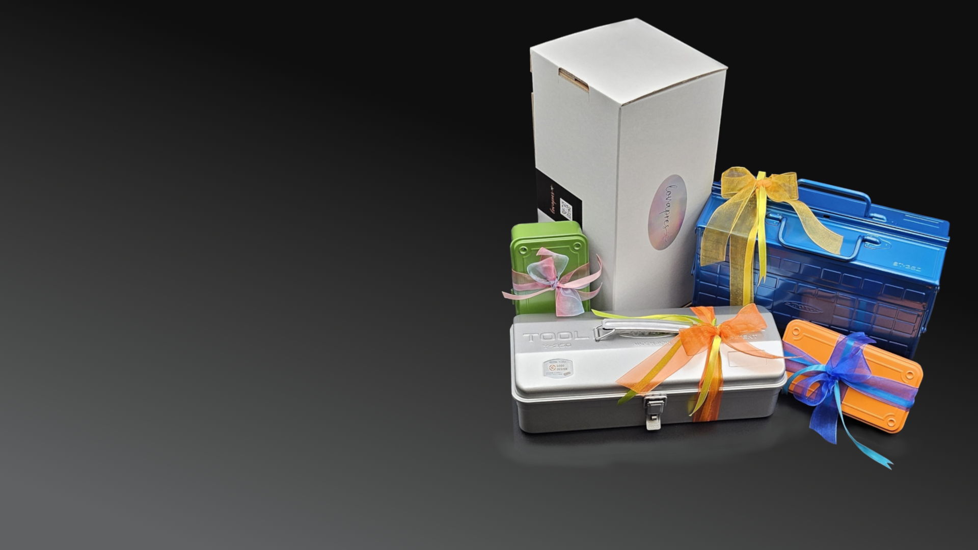 Geschenkboxen in Blau, Orange, Grün und Silber mit bunten Schleifen auf schwarzem Hintergrund