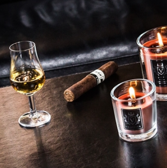 Brennende braune Kerze in einem eleganten Glasgefäss, auf einem Tisch arrangiert – verbreitet warmes Licht und Gemütlichkeit.