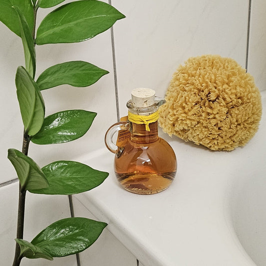 Dekoratives Glas mit Honig-Schaumbad und Naturschwamm am Wannenrand – natürliches Badeambiente.