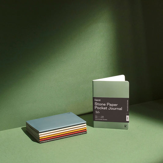 A6 Taschenjournals in verschiedenen Farben auf grünem Hintergrund