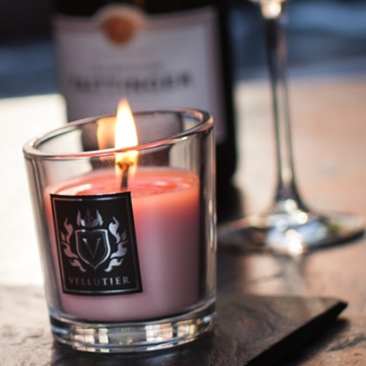 Angezündete rosa Duftkerze in dekorativem Glas auf einem Tisch – sorgt für stimmungsvolles Ambiente.