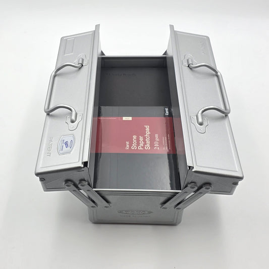 Offene Toyo Metallbox mit Skizzenblock und Farbstiften im Inneren