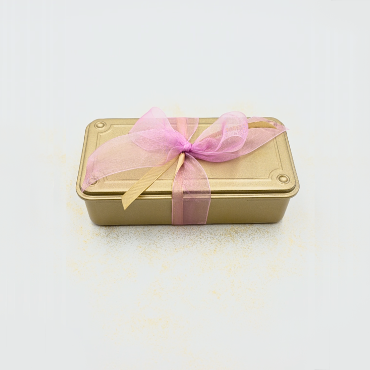 Geschlossene goldene Geschenkbox mit rosa Schleife, elegant verpackt, ideal als Beauty-Geschenk für Silvester, Partys oder besondere Anlässe.