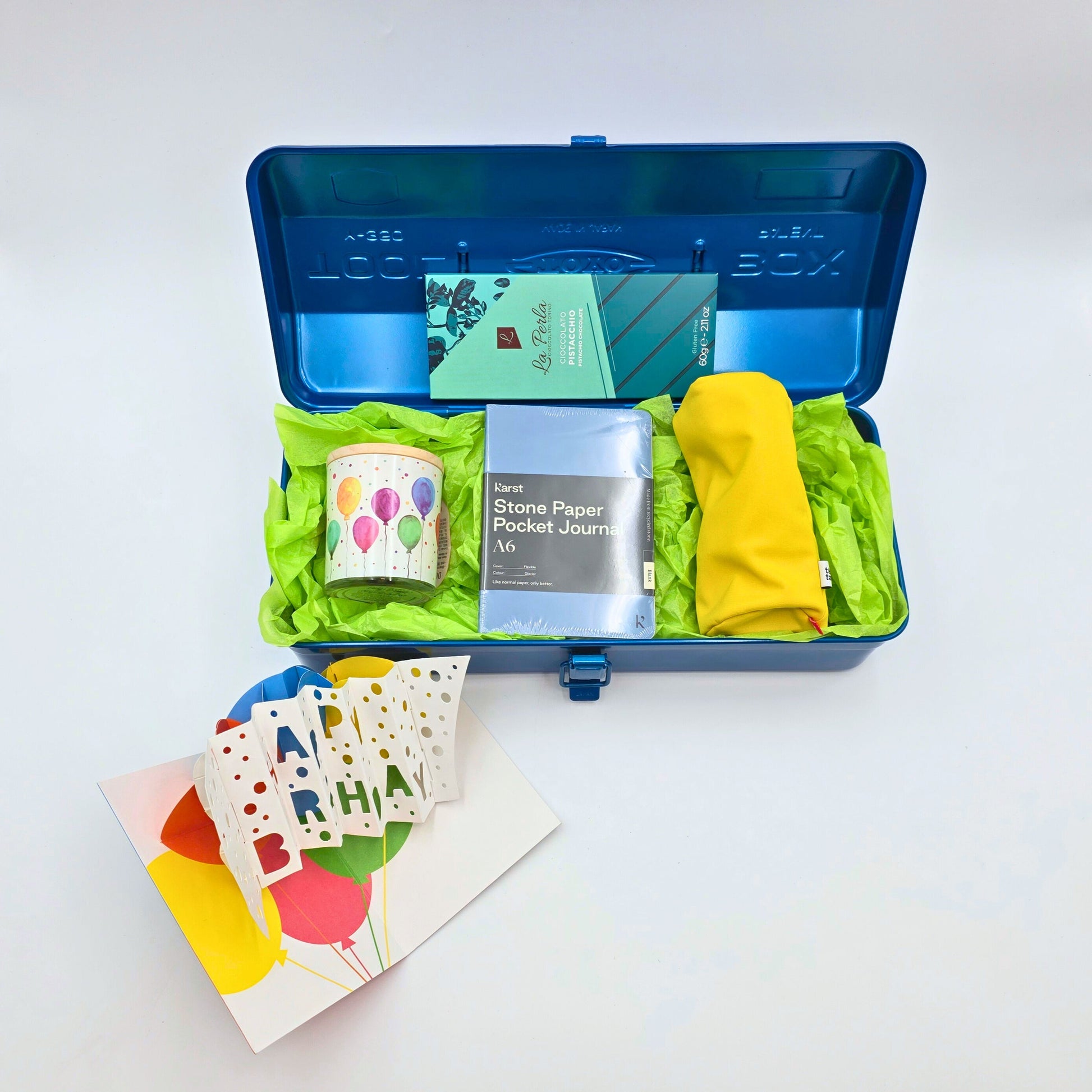 blaue Geschenkbox offen mit verschiedenen Produkten und einer Geburtstagskarte