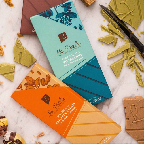 Schokoladentafeln Pistazie und Erdnuss in Blau und Orange, mit Bruchstücken rundherum