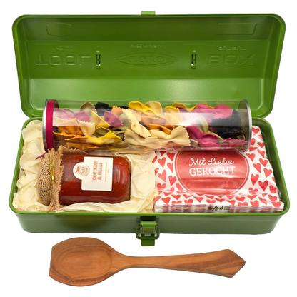 Grüne Toyo Stahlbox gefüllt mit Tomatensauce, bunte Farfalle, Holzlöffel und Serviette - perfektes Geschenk für Hobbyköche