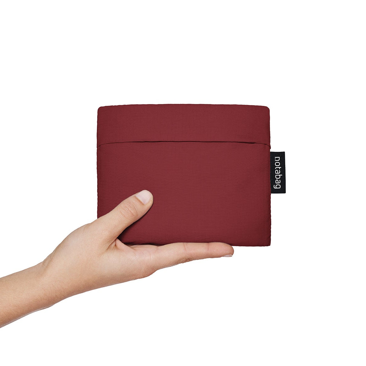 Nachhaltige, faltbare Notabag in Weinrot, die sich von einer Tragetasche in einen Rucksack verwandelt. Praktischer Begleiter für Stadt und Velo.