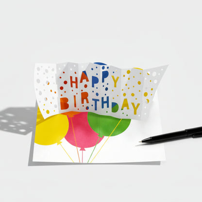 Geöffnete Pop-up-Grusskarte mit Luftballons und Happy Birthday Schriftzug, Kugelschreiber als Grössenreferenz