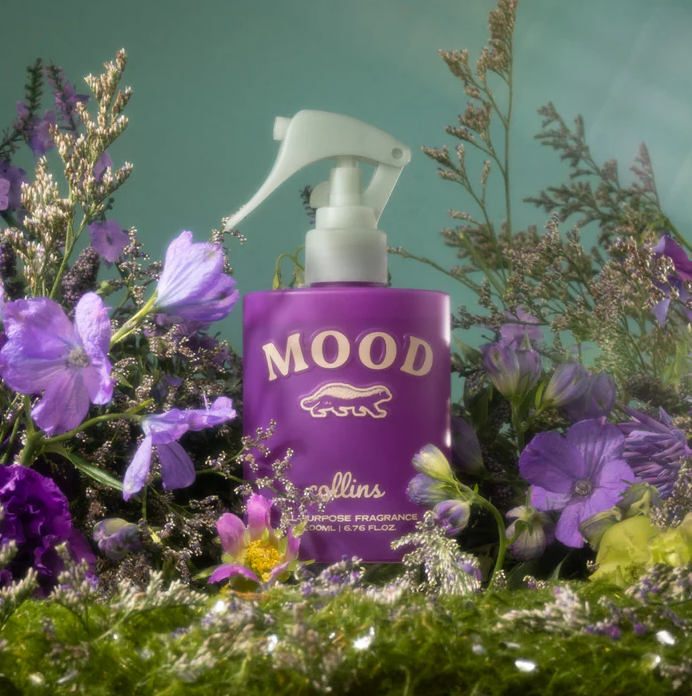Lila Collins Mood Water Raumspray inmitten blühender violetter Blumen – Pflanzliches Textilspray und Raumduft mit blumigem Duft für ein ästhetisches Wohnambiente.