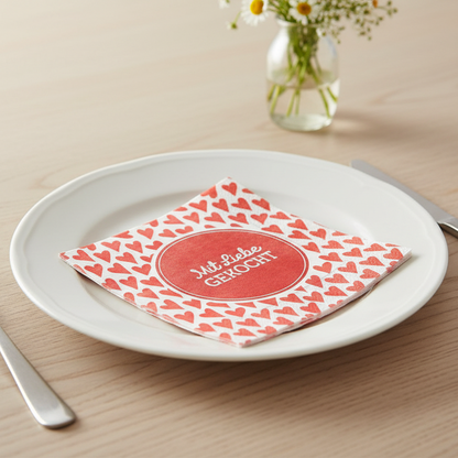 Schöne Rote Serviette mit Herzen und Aufdruck ''mit Liebe gekocht'' auf dem Esstisch