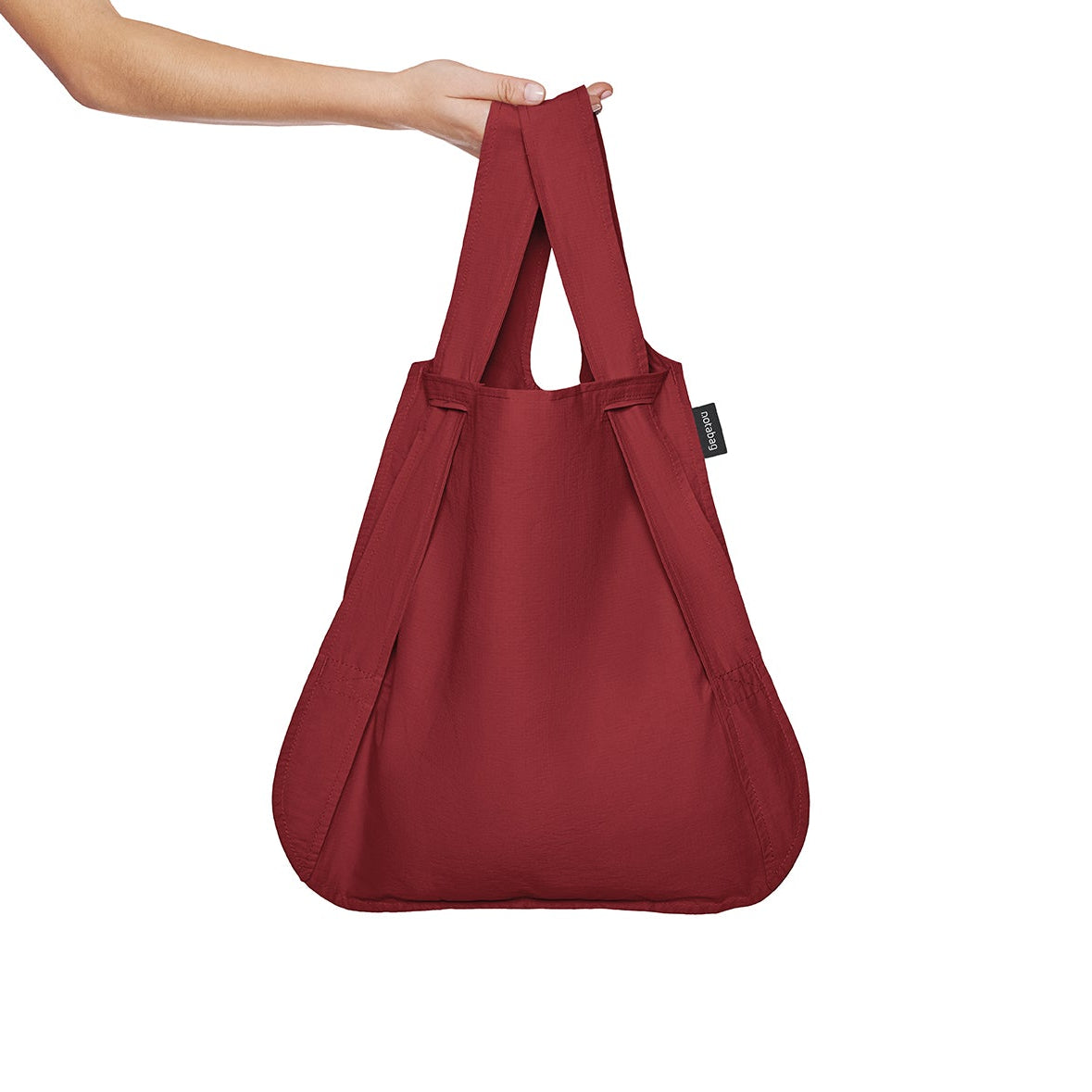 Weinrote Notabag – vielseitige Hybrid-Tasche, die als Rucksack oder Tragetasche genutzt werden kann. Platzsparend und umweltfreundlich.