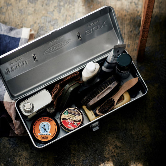 Silberfarbene Werkzeugkasten gefüllt mit Schuhpflege Set