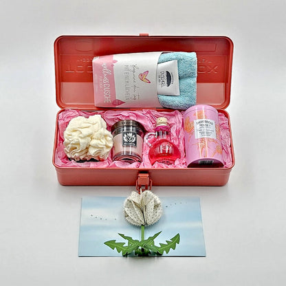 Wohlfühlzeit coralfarbene Geschenkbox mit geöffnetem Deckel, zeigt den Inhalt mit verschiedenen Produkten.