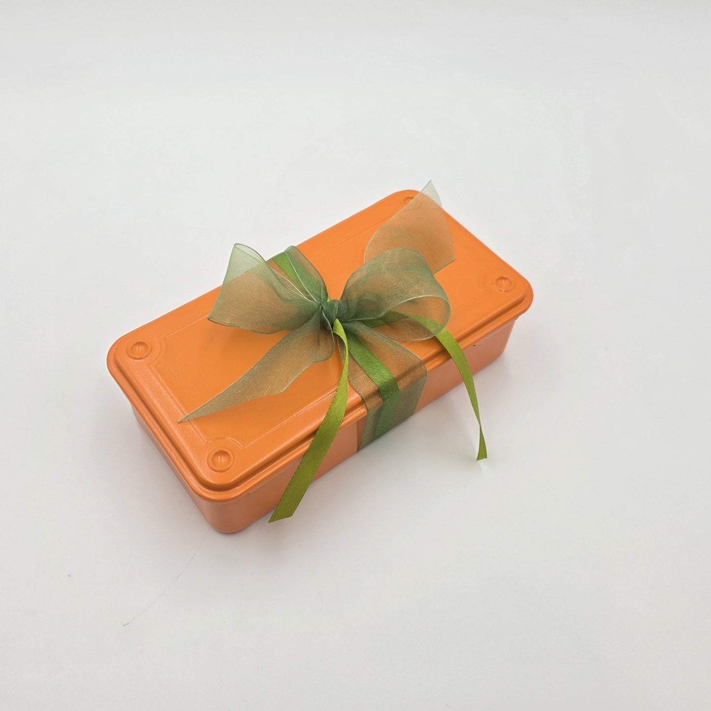 Geschlossene Orange Power Geschenkbox in einer orangenen Box mit grüner Schleife.